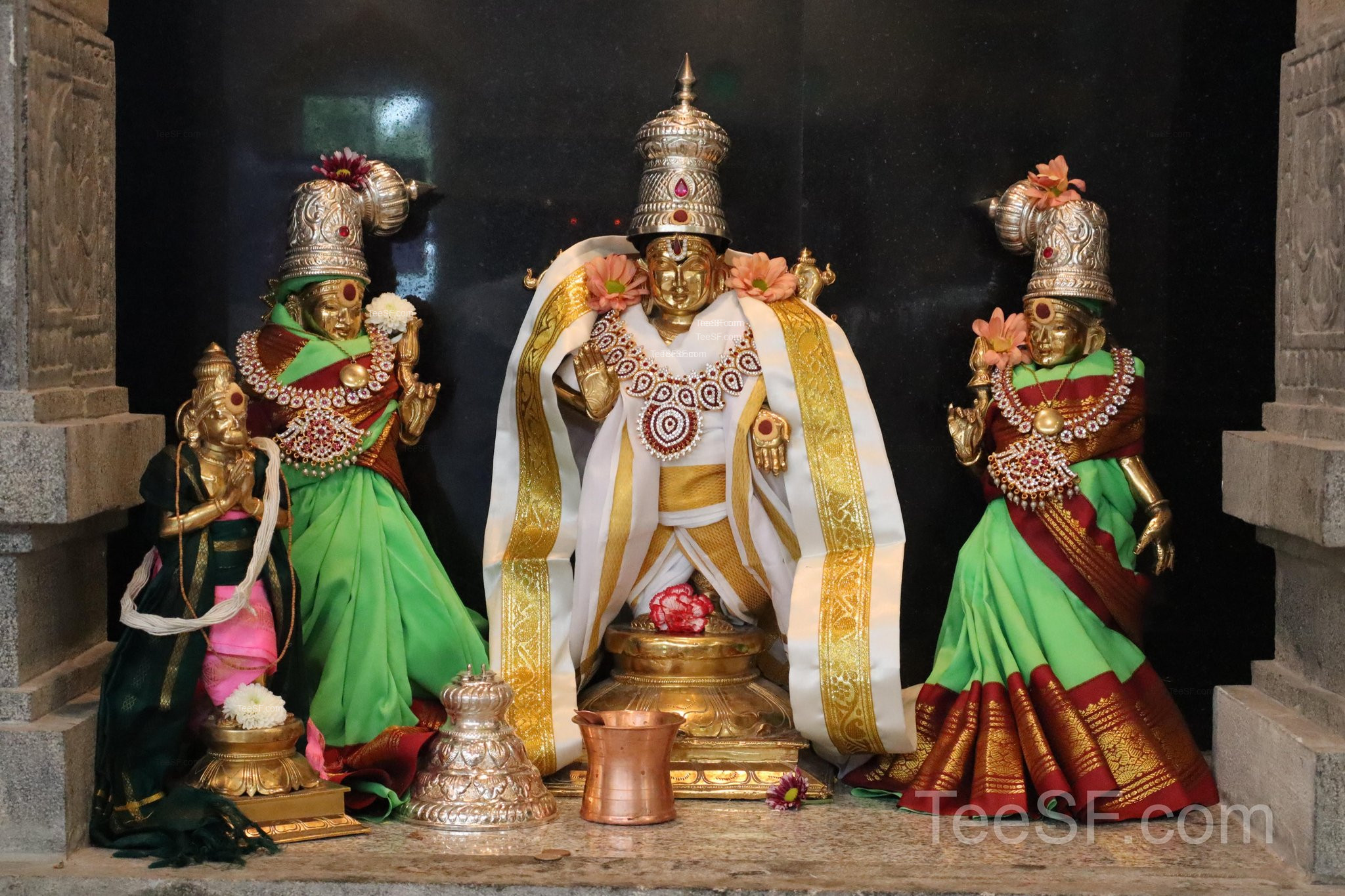 A central deity shrine with two colorful figures on either side.